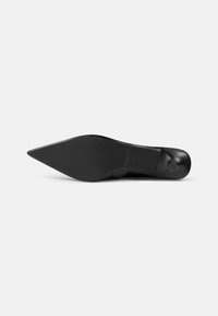 Black high-heeled shoe with a pointed toe, smooth texture, and a rubber outsole featuring subtle tread patterns.