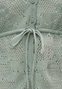 Ανοιχτό πράσινο πλεκτό ένδυμα με κουμπιά και δεμένο κορδόνι στη μέση, με δαντελένιο μοτίβο σε όλο το ύφασμα.