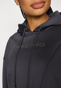 Black hoodie with adjustable drawstrings, featuring a subtle "NIKE PRO" logo, made of a smooth, stretch fabric with seam detailing.