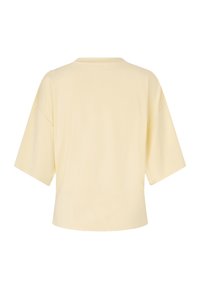 Μπεζ T-shirt με κοντά μανίκια και χαλαρή εφαρμογή, που φαίνεται από πίσω, με απλή στρογγυλή λαιμόκοψη και χωρίς εμφανή μοτίβα ή λογότυπα.