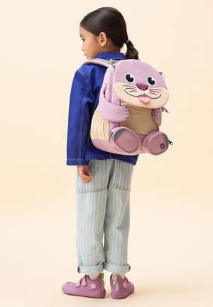 Child with dark hair in a ponytail wearing light striped pants, a blue jacket, pink shoes, and a purple animal-themed backpack.