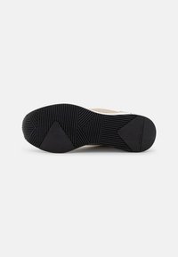 Suola di scarpa in gomma nera con un motivo testurizzato che presenta delle scanalature e un logo. Il design è angolare con un'area del tallone rinforzata.