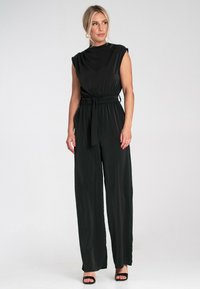 Czarny kombinezon bez rękawów z wysokim kołnierzem, elastyczną talią i pasującym paskiem, z szerokimi spodniami i gładką, zwiewną fakturą.