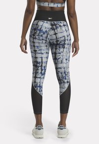 Leggings con un patrón geométrico azul y gris, cintura alta negra y detalles negros en los laterales, fabricados con un material elástico y transpirable.
