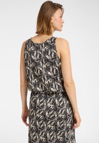 Abito senza maniche con un motivo astratto in nero e crema, caratterizzato da una vestibilità ampia e una vita arricciata, realizzato in tessuto leggero.