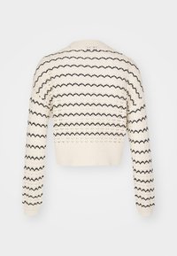 Pull en tricot coupé crème avec des rayures en zigzag noires. Doté de poignets et d'un ourlet côtelés, ainsi qu'un motif de tricot texturé sur l'ensemble.