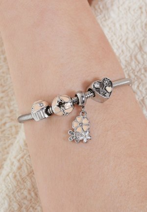 Sterling silver bracelet with dangling flower charm, featuring enamel and crystal accents, smooth texture, and various bead shapes in pastel colors.