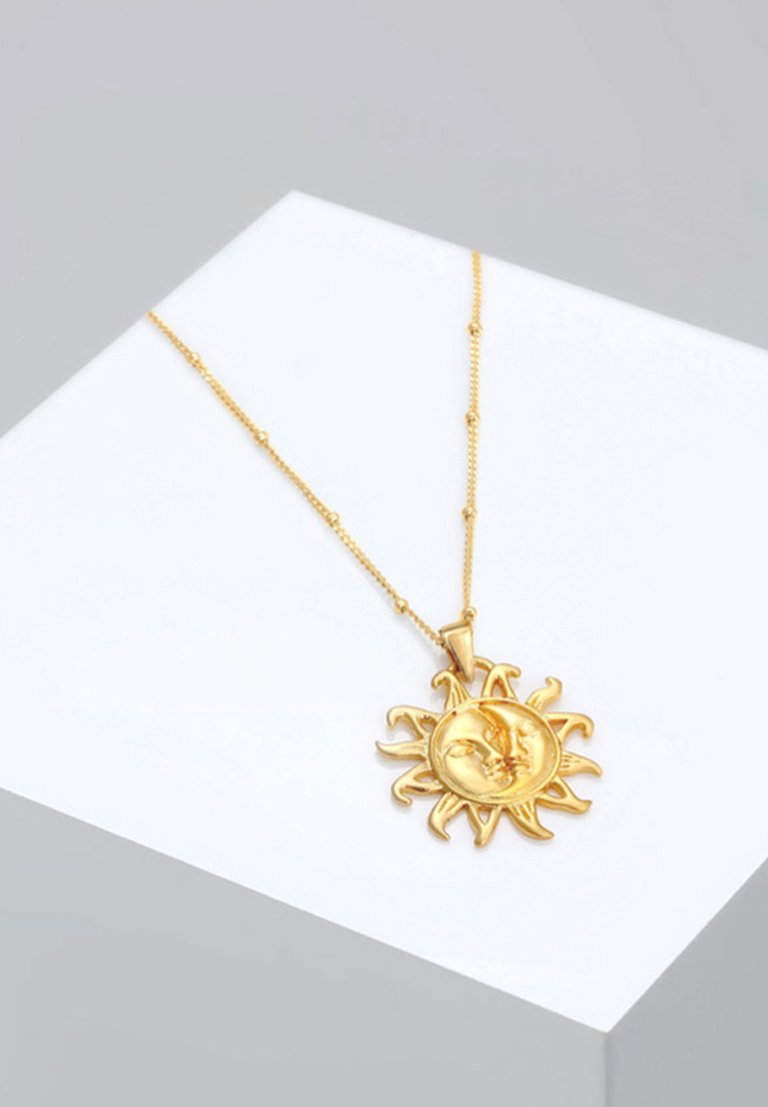 Goldanhänger mit einem Sonnendesign, das ein detailliertes Gesicht und hervortretende Strahlen zeigt, hängt an einer zarten Kette.