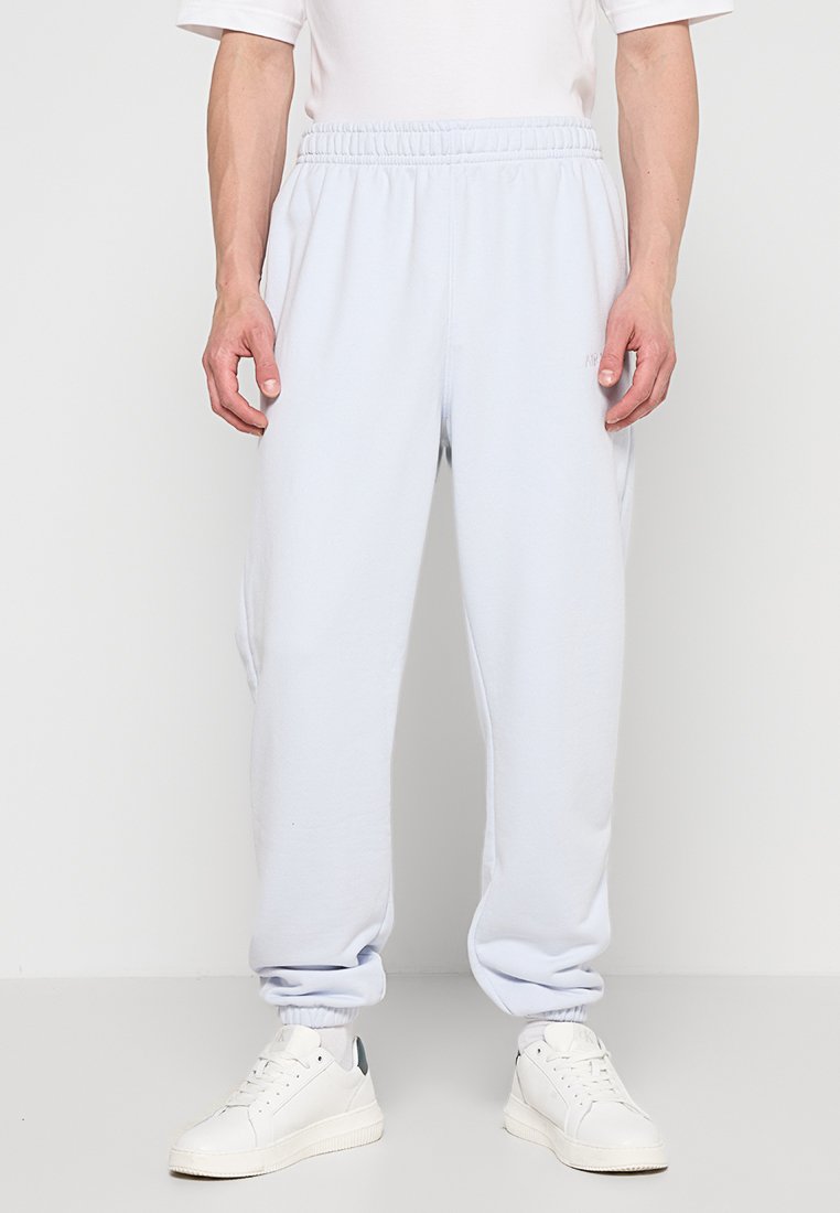 Helleblaue Sweatpants aus weichem Material, mit einem elastischen Bund und cuffs an den Säumen, kombiniert mit weißen Sneakern.