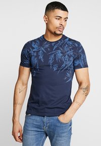 Navy blue short-sleeve t-shirt with a textured leaf pattern in dark blue, round neckline, and a fitted shape.