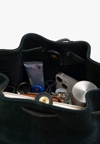 Schwarze Bucket-Bag aus Leder mit weicher Textur. Im Inneren befinden sich eine Handcreme, ein Smartphone, Schlüssel und ein Metallbehälter, alle ordentlich organisiert.