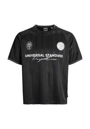 Maglietta nera a maniche corte con colletto tondo, caratterizzata da righe verticali, due stampe del logo e "UNIVERSAL STANDARD ProjectCore" in testo bianco.