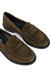 Brązowe zamszowe mokasyny z przeszyciami i akcentem w postaci chwosta, z niskim czarnym obcasem i gładkim wykończeniem wnętrza.