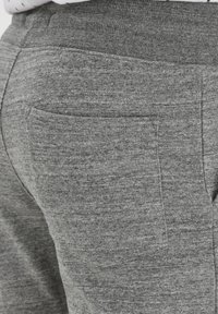 Gray sweatpants featuring a textured fabric, a stretchy waistband, and a single back pocket with a clean, minimal design.