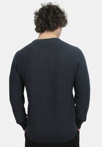 Maglione blu navy, texture a coste, maniche lunghe, colletto a girocollo, design aderente e colore uniforme. Nessun motivo visibile o dettagli in metallo.