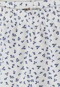 Tissu blanc côtelé avec de petites brindilles florales bleu foncé, ceinture élastique et étiquette de marque Minoti pour enfants de 4 à 5 ans.
