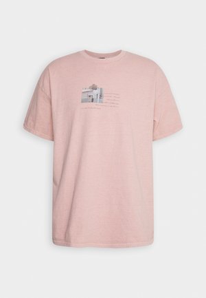 Różowy bawełniany T-shirt o luźnym kroju, z nadrukiem graficznym na środku, zawierającym tekst i element fotograficzny. Krótkie rękawy i okrągły dekolt.