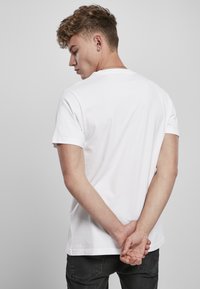 White cotton t-shirt with short sleeves, round neck, and a relaxed fit, paired with dark jeans. No patterns or logos visible.