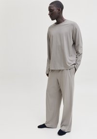 Haut à manches longues gris clair et pantalon ample en tissu doux, présentant un design simple sans motifs ni accents visibles.