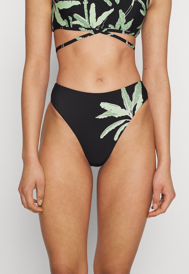 Μαύρο μπικίνι με σχέδιο από φύλλο φοίνικα σε πράσινο χρώμα; ψηλόμεσο κάτω μέρος με σχεδιαστική λεπτομέρεια στο πλάι. Το υλικό φαίνεται απαλό και ελαστικό.