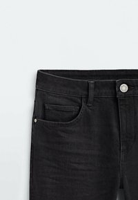 Jeans en denim noir avec un design classique à cinq poches, dotés d'une fermeture éclair, d'un bouton et de détails de couture subtils le long des coutures.