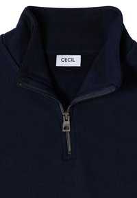 Pullover in navy con zip e colletto alla cinese, dotato di una cerniera metallica argentata. Il tessuto è liscio con una texture a coste sul colletto. L'etichetta riporta "CECIL."
