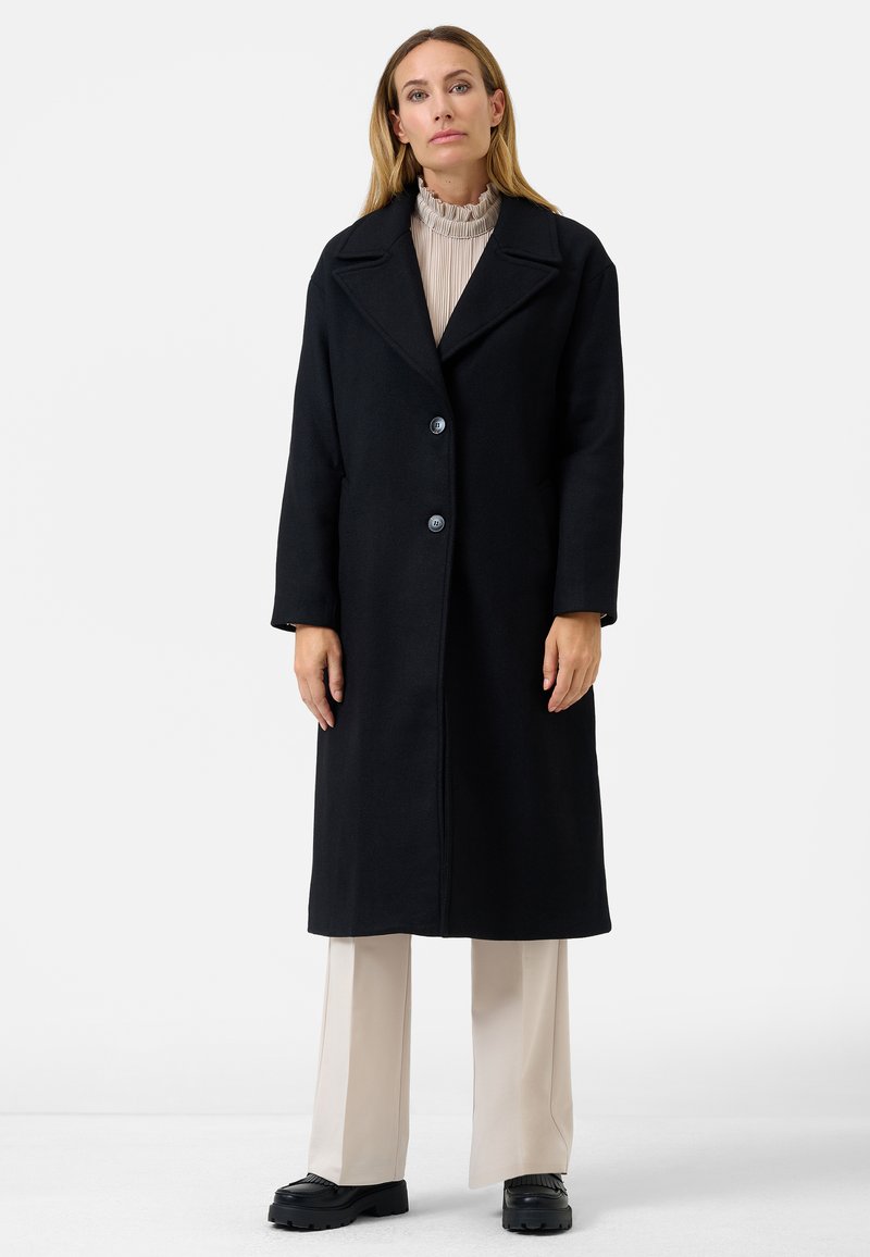 Black wool overcoat with a notch collar, single-breasted two-button closure, and side pockets. Smooth texture and long design.
