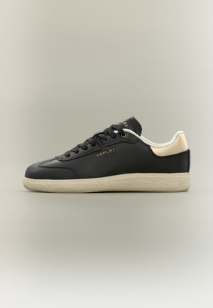 Baskets basses noires avec semelle et talon beige, lacets noirs et logo doré "REPLAY" sur le côté et la languette.