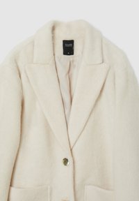 Blazer in misto lana color crema con rever a scollo, due tasche frontali e chiusura con un solo bottone dorato. Interno foderato.