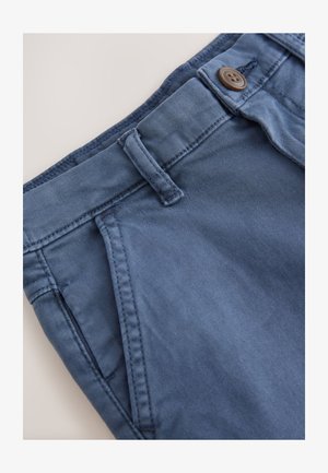 Sötétkék pamut nadrág klasszikus derékpánttal, gombos záródással és oldalzsebekkel, melyeken tónusú varrással díszített részletek találhatók.