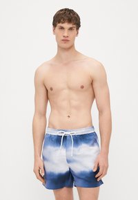 Mėlyni ir balti ryškiai dryžuoti maudymosi šortai su elastinga juosmens juosta, raišteliu ir trumpu ilgiu, pasižymintys lygiu audinio tekstūra.