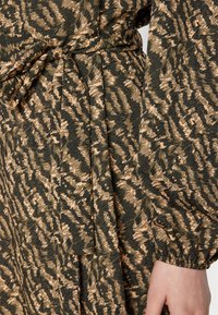 Φορεμα με σχέδιο που διαθέτει αφηρημένο μοτίβο σε μαύρο και μπεζ χρώμα, υφασμάτινη υφή, συρραμμένη μέση με κορδόνια και ελαστικούς καρπούς.