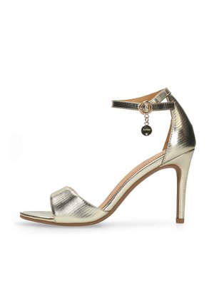 Metalen gouden sandaal met hoge hak, een getextureerd oppervlak, open teen, een enkelbandje en een decoratieve bedel aan het bandje.