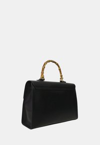 Borsa a mano in pelle nera con una silhouette strutturata, manico in bambù e dettagli in metallo dorato. Texture liscia con minimalismo nei dettagli.