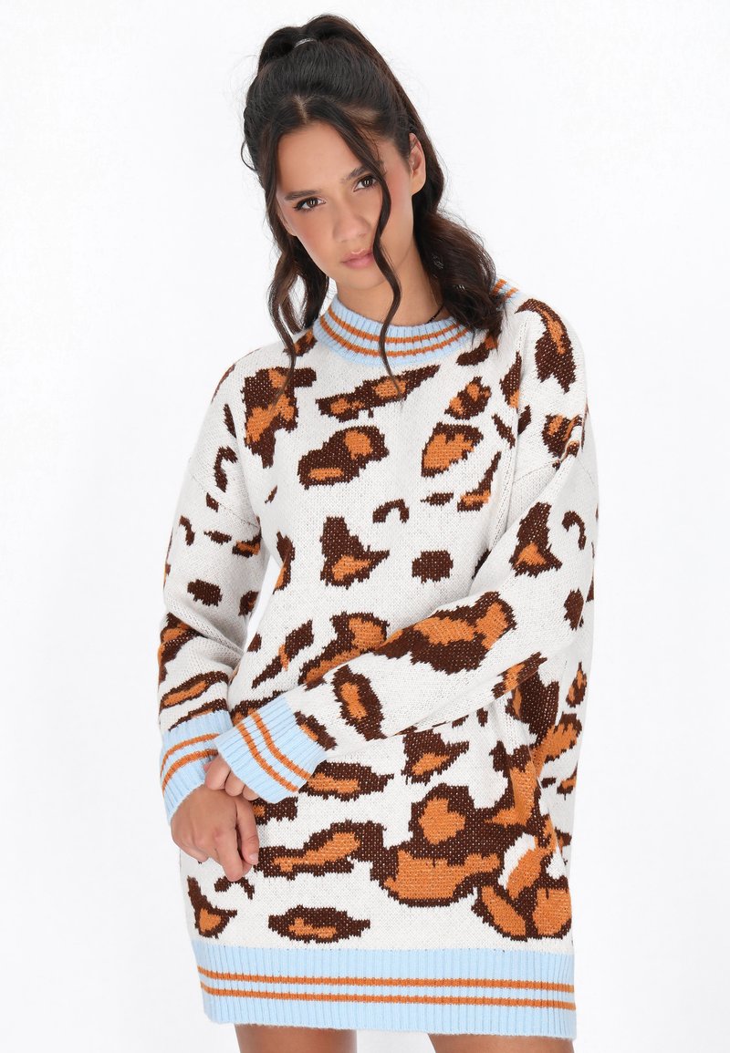 Overdimensioneret sweater i strikket materiale, med en hvid bund og brune leopardpletter, samt blå og orange stribede manchetter og krave.