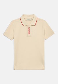 Béžová polo tričko s červeným golierom a vyšitým logom "Calvin Klein" na ľavej hrudi. Krátke rukávy, bočné rozparky na leme.