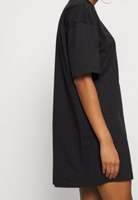 Svart oversize T-shirt i bomull. Kort ärm, rund halsringning, sidoflikdetalj och en mjuk yta.