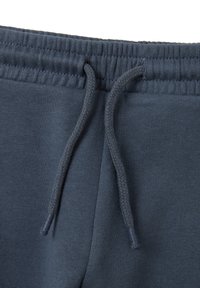 Un pantalon de jogging bleu foncé avec une taille élastique, un cordon de serrage tressé et une texture lisse, idéal pour un usage décontracté.