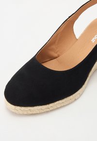 Černé semišové espadrilky s kulatou špičkou a platformou z juty, mají měkké béžové vnitřní podšívky a design na patu.