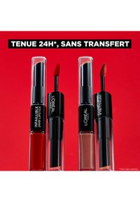 Trois rouges à lèvres L'Oréal Infallible 24HR dans des tubes transparents, comprenant une teinte rouge et deux teintes nude, avec des applicateurs en éponge et des accents noirs.