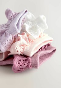 Una pila di cinque coppie di calzini colorati in lavanda, bianco, rosa e rosa scuro. Ogni calzino presenta un bordo di pizzo con ritagli floreali.
