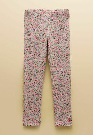 Rozā legingi ar blīvu sarkanu, zilu un zaļu ziedu un lapu rakstu, izklāti uz bēša fona.