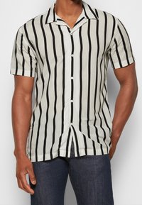 Korte mouwen overhemd met knopen in roomkleur met zwarte verticale strepen, voorzien van een inkepingkraag en een gladde stoftextuur.