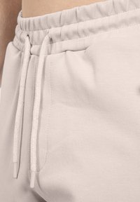 Lysegrå sweatpants har en samlet elastisk talje med snørebånd og en glat, blød stoftekstur.