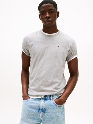 Gray short-sleeve t-shirt with white rolled cuffs, featuring a small logo. Paired with light blue denim jeans, hands in pockets, neutral background.