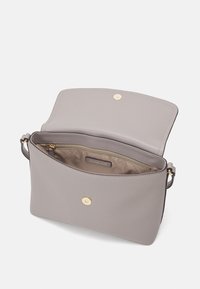 Sac en cuir gris clair à bandoulière avec fermeture magnétique dorée, doublure intérieure beige et poche zippée intérieure étiquetée Michael Kors.