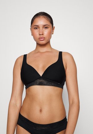 Black wireless bra with a plunging neckline and adjustable straps. Features a lace band at the bottom with floral patterns. Smooth fabric texture.