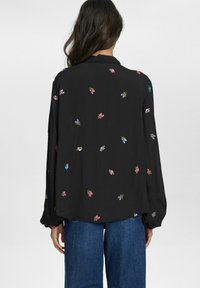 Schwarze Bluse aus leichtem Stoff, mit mehrfarbigem Blumenstickerei, langen Ärmeln und lockerer Passform.