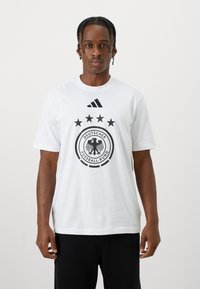 Hvit bomull T-skjorte med en svart logo fra det tyske fotballforbundet og fem stjerner over, med et Adidas-logo øverst.