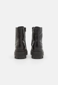 Black leather ankle boots with a textured finish, featuring a side zipper and chunky rubber sole, designed for durability and support.